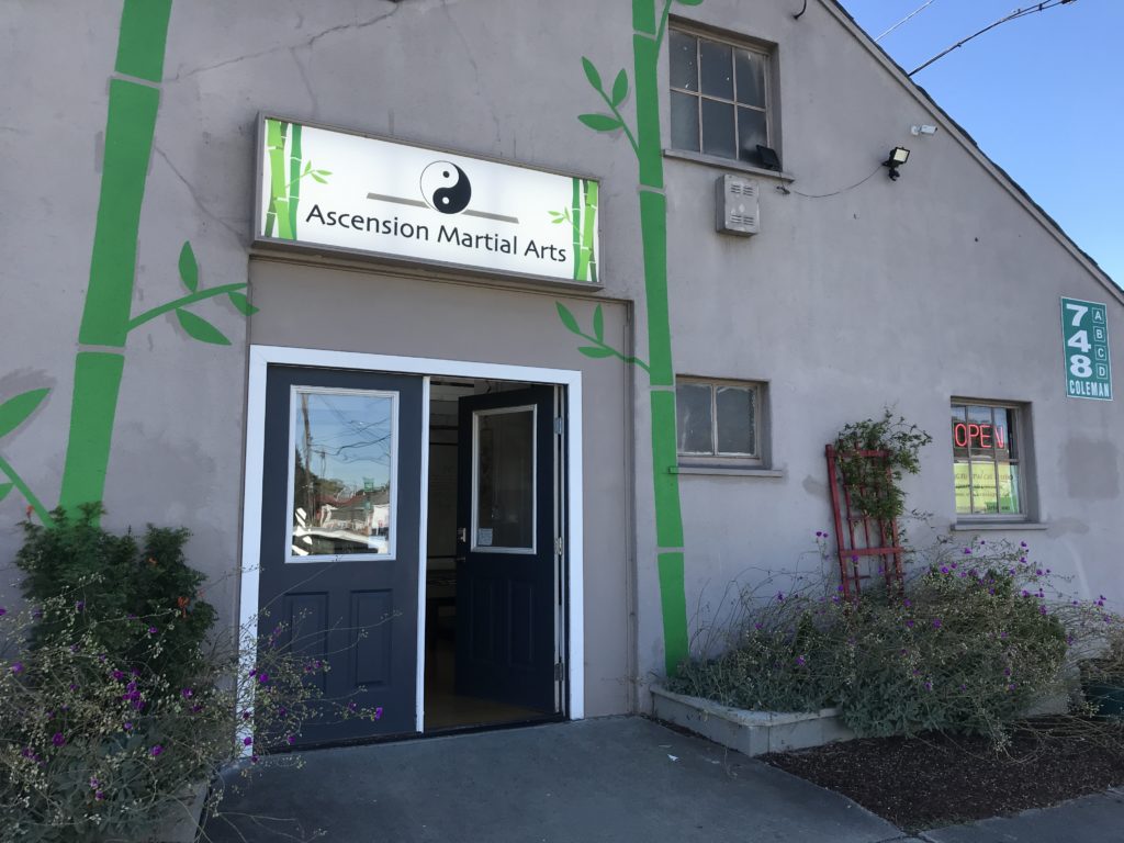 Front of school with lit sign, painted bamboo sides, and open door